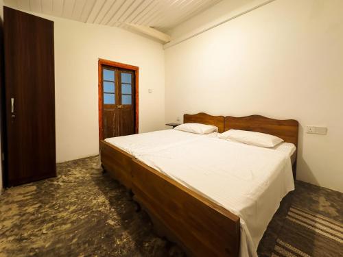 a bedroom with a large bed with a wooden headboard at House of Merchants in Galle