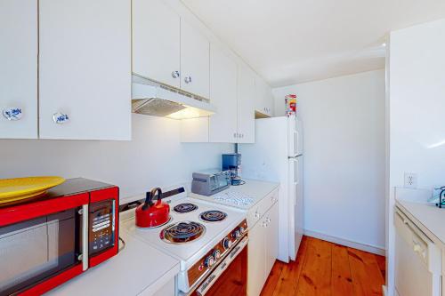 a kitchen with white cabinets and a stove top oven at Maushop By The Sea in Mashpee