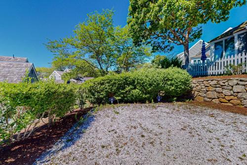 a yard with a stone wall and a house at Maushop By The Sea in Mashpee