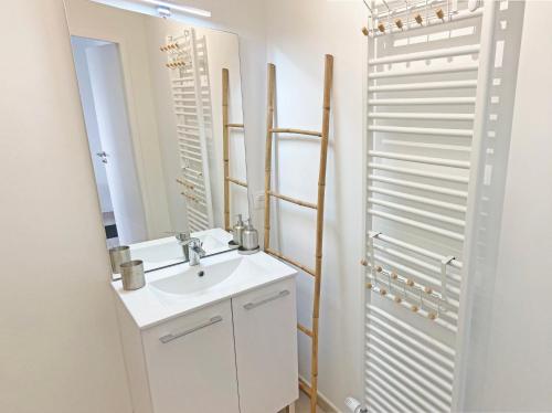 une salle de bain blanche avec un lavabo et un miroir dans l'établissement Rooftop terrasse vue phare et mer, à Berck-sur-Mer