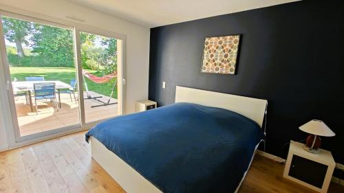 - une chambre avec un lit bleu et une porte coulissante en verre dans l'établissement Maison familiale au cœur du pays de Brocéliande, à Montfort-sur-Meu