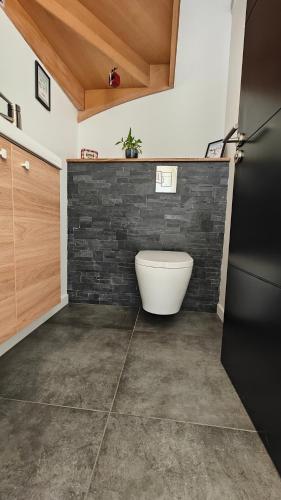 La salle de bains est pourvue de toilettes blanches et d'un mur en briques. dans l'établissement Maison familiale au cœur du pays de Brocéliande, à Montfort-sur-Meu