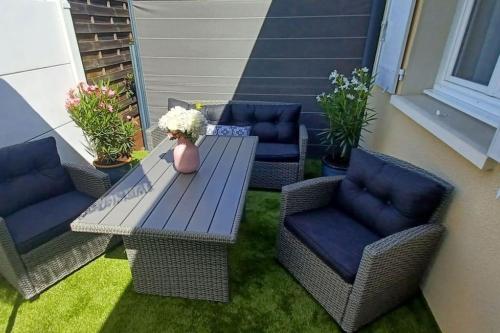 d'une terrasse avec des chaises et une table ornée d'un vase de fleurs. dans l'établissement Appartement 2 pièces, 1 chambre, terrasse, à Gujan-Mestras