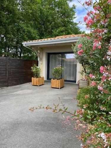 une maison avec deux plantes en pot dans une allée dans l'établissement Appartement 2 pièces, 1 chambre, terrasse, à Gujan-Mestras