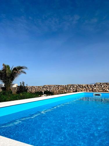 a blue swimming pool with the beach in the background at Apartments PUPA in Povljana