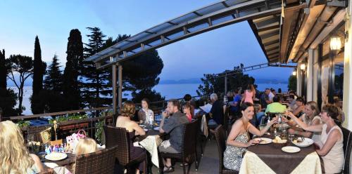 a group of people sitting at tables at a restaurant at Camping Bella Italia in Peschiera del Garda