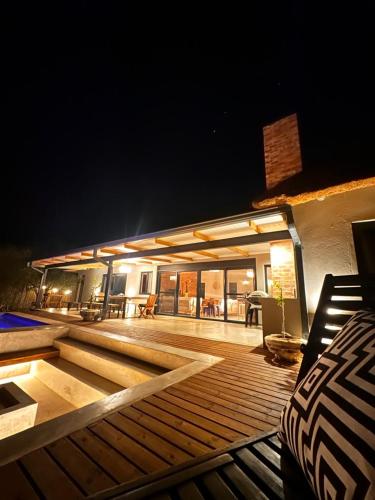 a wooden deck with chairs and a building at night at Pumba Lodge Hoedspruit in Hoedspruit