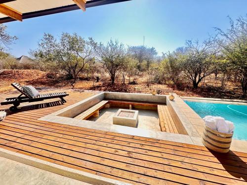 a deck with a pool and a bench next to a swimming pool at Pumba Lodge Hoedspruit in Hoedspruit
