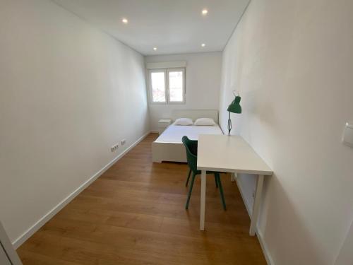 a white room with a table and a bed at Carcavelos Beach Shared Serviced Apartment 12 in Oeiras