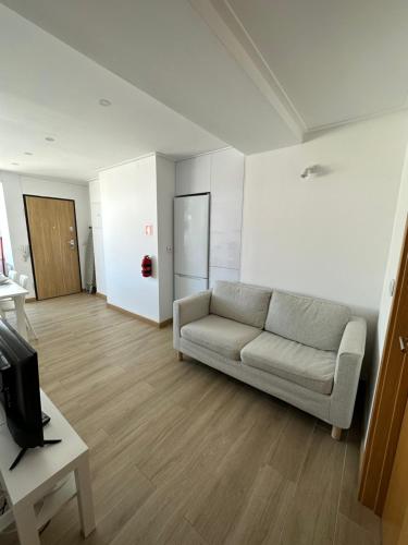 a living room with a couch and a tv at Carcavelos Beach Shared Serviced Apartment 12 in Oeiras