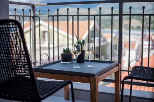 a table with two glasses of wine on a balcony at De Bosset Suites Kefalonia in Argostoli