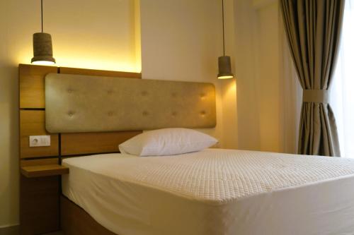 a bedroom with a white bed with two pendant lights at BluMango Resort in Ierissos