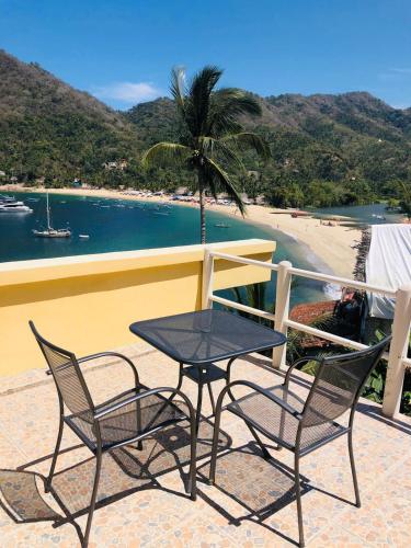 a table and two chairs on a balcony with a beach at Casa Berita in Yelapa
