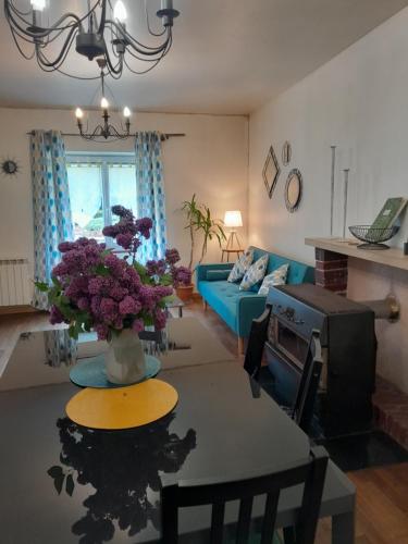un salon avec un canapé bleu et une table avec des fleurs violettes dans l'établissement Gite 
