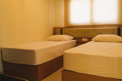 two twin beds in a room with a window at BluMango Resort in Ierissos