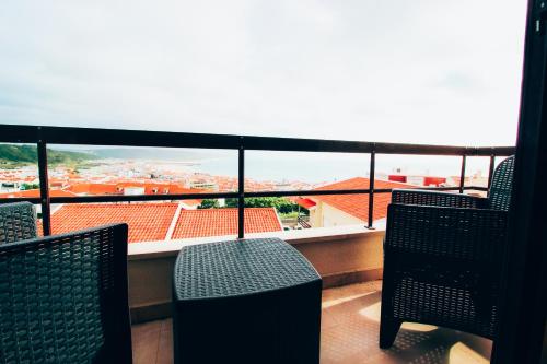 a balcony with chairs and a view of a city at Flor do Mar in Nazaré