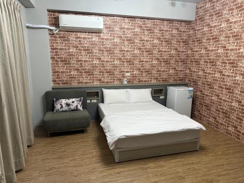 a bed and a chair in a room with a brick wall at 丹藍民宿 in Magong