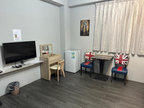 a room with a tv and chairs and a table at 丹藍民宿 in Magong