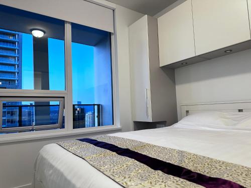 a bedroom with a bed and a large window at Monthly stay-Relocation Special-New condo at Metrotown in Burnaby