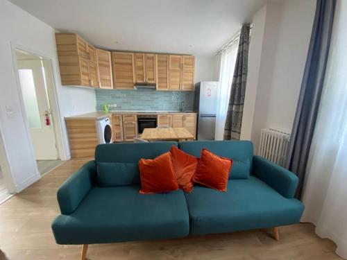 - un canapé bleu avec deux oreillers orange dans la cuisine dans l'établissement Appartement Colombes - 12min de PARIS, à Colombes