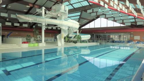 une grande piscine avec un toboggan aquatique dans l'établissement Maison familiale au cœur du pays de Brocéliande, à Montfort-sur-Meu