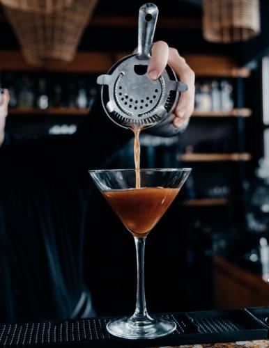 a bartender making a cocktail in a martini glass at Hotel Cruz del Vado by Art Hotels in Cuenca