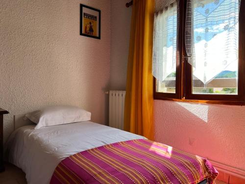 a small bedroom with a bed and a window at La Charmante in Le Vigan