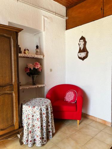a red chair and a table in a room at La Charmante in Le Vigan