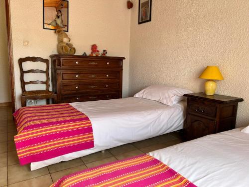 a bedroom with two beds and a dresser and a chair at La Charmante in Le Vigan