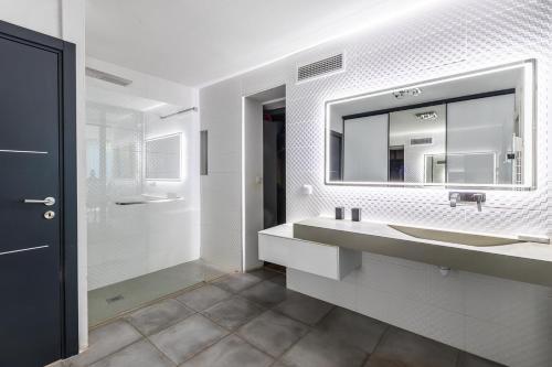 une salle de bain blanche avec un lavabo et un miroir dans l'établissement st clair villa 2 piscines, à Sète