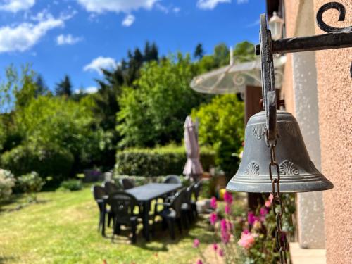 a bell on the side of a house with a table and chairs at La Charmante in Le Vigan