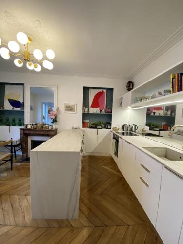 une cuisine avec des placards blancs et un grand îlot dans l'établissement Cozy Haussmanian flat in the heart of Paris, à Paris