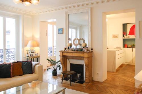 un salon avec une cheminée et un miroir dans l'établissement Cozy Haussmanian flat in the heart of Paris, à Paris