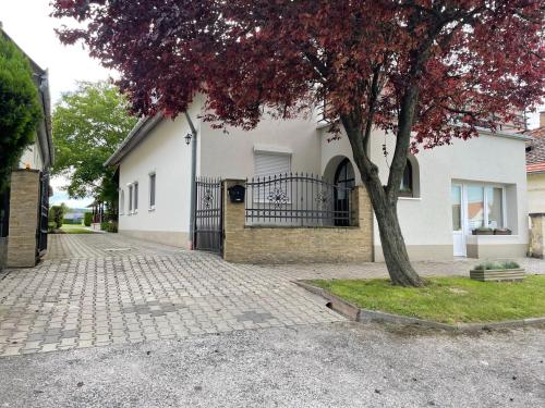 a white house with a tree in front of it at Margaret Apartment in Balatonkeresztúr