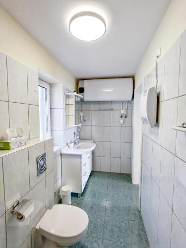 a white bathroom with a toilet and a sink at Fügefa Apartman in Balatonalmádi