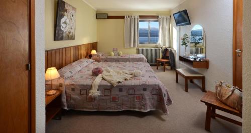 Una habitación de hotel con dos camas y un escritorio. en Hotel Aconcagua, en San Carlos de Bariloche
