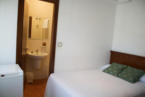 a bedroom with a bed and a bathroom with a sink at Pension Santos in Vimianzo
