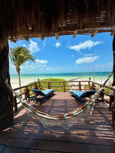 a hammock on a deck with chairs and the beach at DK Luxury Ocean Front Villa - Adults Only in Holbox Island