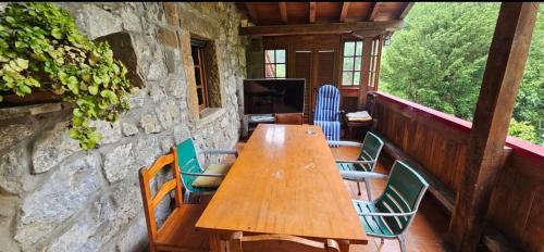 a wooden table and chairs on a porch at Finca la Vegacha casa tradicional pasiega in San Roque de Ríomiera