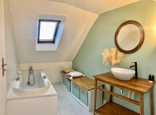 a bathroom with a tub and a sink and a mirror at Ty Glaz Lilia - La maison bleue in Plouguerneau