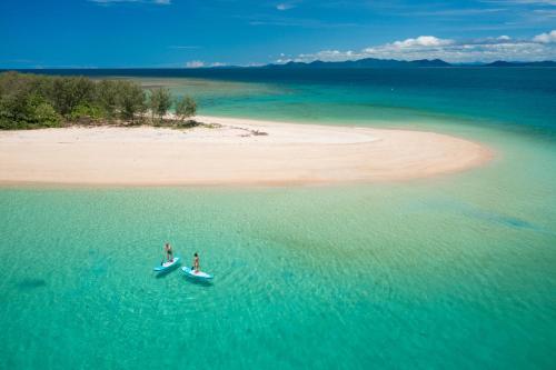 two people on a boat in the water near a beach at Cairns Rainforest Retreats in Bellenden Ker