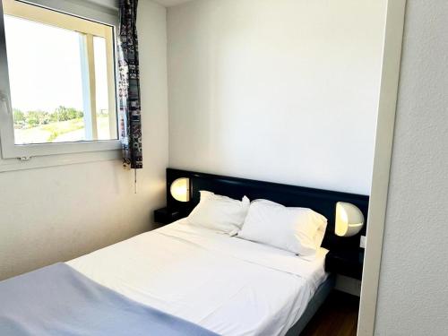 une chambre avec un lit avec des draps blancs et une fenêtre dans l'établissement Résidence Le Boucanier - 2 Pièces pour 4 Personnes 291, à Vieux-Boucau-les-Bains