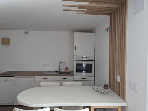 une cuisine blanche avec une table et des chaises blanches dans l'établissement Appartement cosy Fraisses, à Fraisse
