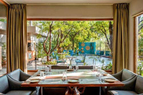 a dining room with a table and chairs and a large window at Giovanni Village Resort in Bhopal