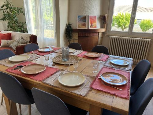 une table en bois avec des assiettes et des verres à vin dessus dans l'établissement Maison de vacance Talmont st hilaire, à Saint-Hilaire-de-Talmont