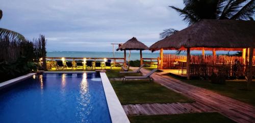 a resort with a swimming pool with a view of the ocean at Pousada Taipa dos Milagres in São Miguel dos Milagres
