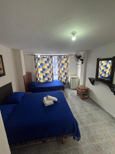 a bedroom with two blue beds and a tv at Casa hotel villadiana in Armenia