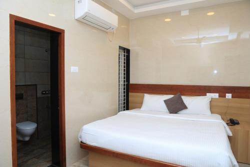 a bedroom with a white bed and a bathroom at TCS Residency in Kanchipuram