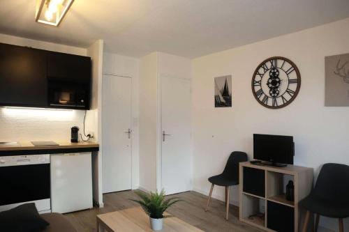 - un salon avec un bureau et une horloge murale dans l'établissement Résidence L'oustal - Joli studio équipé pour 6 personnes MAE-1461, aux Orres