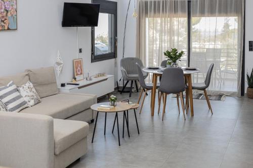 a living room with a couch and a table and chairs at Ammira Mare Apartment in Agia Pelagia